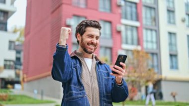 Neşeli adam dışarıda duruyor, heyecanla telefona bakıyor. İyi haber muzaffer bir gülümseme ve yumruk tokuşturma hareketi getirir. Mutluluk ve başarı sahneden yayılıyor..
