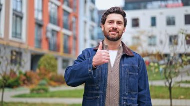 Gülümseyen adam olumlu jest yapar, mutluluk ve güven saçar. Açık havada gerçek duyguların onaylanması ve tatmin olması..
