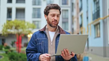 Mutlu adam bilgisayarını kullanarak online video bağlantısı kuruyor. Konuşurken, dijital iletişimi ve modern kentsel yaşamı vurgularken, zevk ve bağlılık hisleri aktarıldı.