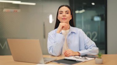 Profesyonel iş kadını ofiste özgüvenle gülümsüyor düşünceli, sakin ve başarıya hazır görünüyor. Planları yansıtmak, ifade etmek zekayı iletir, iyimserliği modern şirket liderliğini..
