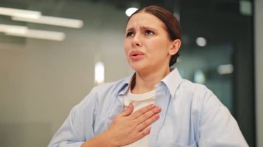 Sıkıntılı kadın göğsünü sıkıyor, keskin bir ağrı ve zorlukla nefes alıyor. Şiddetli rahatsızlık, panik ve olası sağlık sorunları belirtileri gösteriyor. Endişe aşikar..