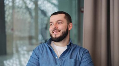 Genç tasarımcı, bilişim uzmanı, sakallı bankacı mutluluk ve iyimserlik saçıyor. Uzağa dikkatlice bakarken nazikçe gülümsüyor. Memnuniyeti ve olumlu duyguyu ifade eder.