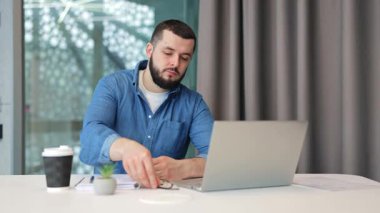 Odaklanmış profesyonel tasarımcı, ciddi ifadeleri olan bilişim uzmanı özenle dizüstü bilgisayarda çalışıyor. Gözlük takmak, konsantre olmak, modern ofiste daktilo yazmak, gayret sarf etmek, profesyonellik..