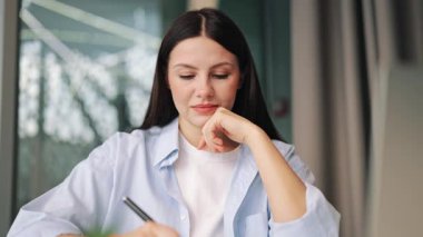 Konsantrasyonunu ve düşüncelerini ifade eden, yazmaya odaklanmış bir kadın. Modern çalışma alanındaki görevlere adanmıştır, ciddi tefekküre işaret eder..