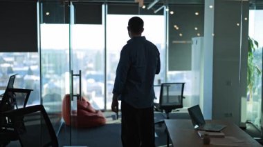 Modern ofis içinde profesyonel duruş, geniş şehir görüşünü gözlemlemek, içgözlem ve hırs duygularını ifade etmek. Düşünce ve gelecek planlama zamanı.