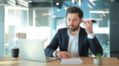 Masada odaklanmış profesyonel, telefon mesajı alıyor, özenle notlar kaydediyor. Bağlı iletişim, modern çalışma alanında verimli görev yönetimi. Konsantrasyon, verimlilik, iş zekası.