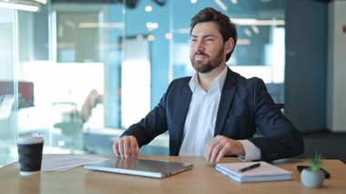 Profesyonel işi bitirir, dizüstü bilgisayarı kapatır. İçerikli birey kollarını uzatır, sandalyede gevşer. Verimli bir işten sonra mutluluk hissi, parlak bir ofiste başarının keyfini çıkarmak..