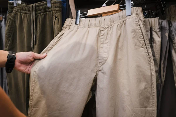 Man choosing pants in shop. Man choosing new trousers in mens cloths store.