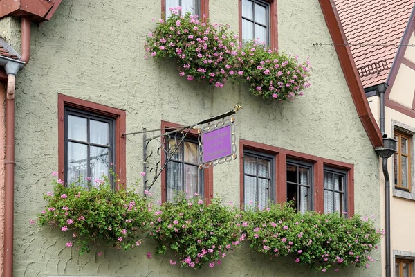 Flower baskets beneath windows in Rothenburg — Stock Photo, Image