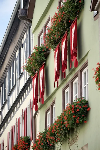 Red geraniums and flags on a house in Rothenburg — Stock Photo, Image