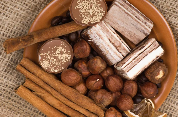 Dulces, canela, nueces y granos de café en un platillo — Foto de Stock