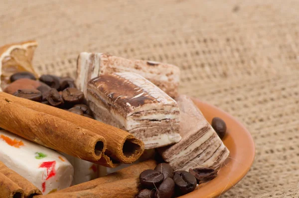 Sweets, cinnamon, nuts and coffee beans on a saucer — Stock fotografie