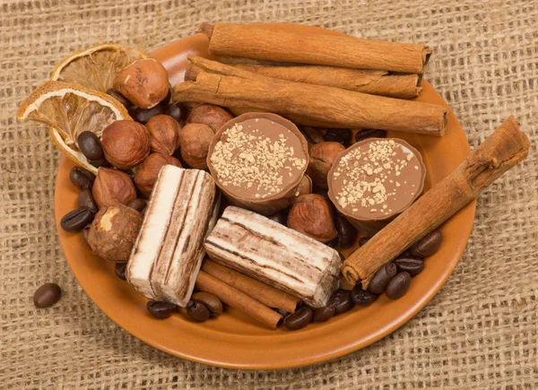 Süßigkeiten, Zimt, Nüsse und Kaffeebohnen auf einer Untertasse, auf Klette — Stockfoto