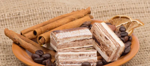 Süßigkeiten, Zimt, Nüsse und Kaffeebohnen auf einer Untertasse — Stockfoto