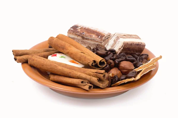 Sweets, cinnamon, nuts and coffee beans on a saucer — Stockfoto