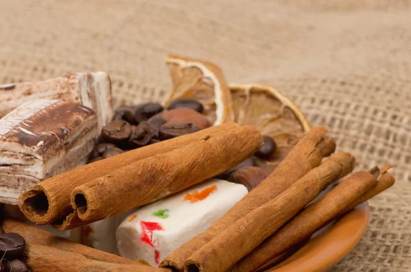 Sweets, cinnamon, nuts and coffee beans on a saucer — Stock fotografie