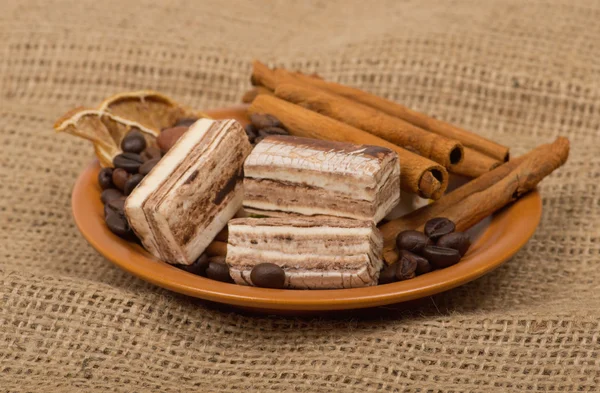 Süßigkeiten, Zimt, Nüsse und Kaffeebohnen auf einer Untertasse. — Stockfoto