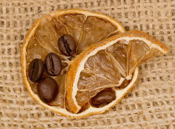 Ломтики лимона и кофейные зерна на мешковине — стоковое фото