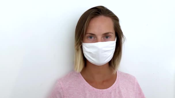 Woman in mask looking at camera on white background covid 19. Empty place text. — Stock Video