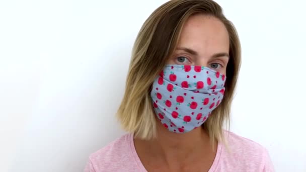 Curiosa kvinna masker tittar på kameran på vit bakgrund coronavirus covid-19. — Stockvideo