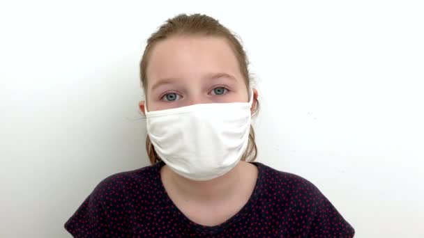 Pensive Porträt Mädchen Kind in Maske Blick in die Kamera auf weißem Hintergrund covid 19 — Stockvideo
