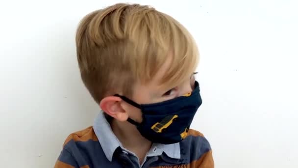 Beau enfant dans la curiosité masque regardant caméra fond blanc coronavirus. — Video