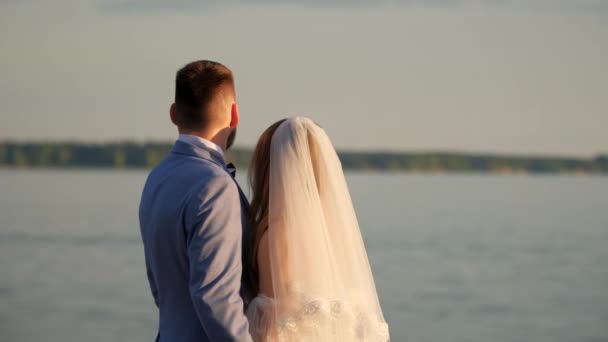 Compromiso novia y novio mirar hacia atrás en la puesta de sol del mar. Pareja feliz boda. — Vídeos de Stock