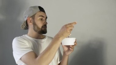 Sakallı adam çilekli dondurma tadıyor ve baş parmağını kaldırıyor. Metnin için yer.