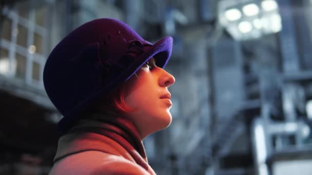 Mujer de estilo moderno en sombrero mirando en el fondo estrella neón iluminación noche ciudad. — Vídeo de stock