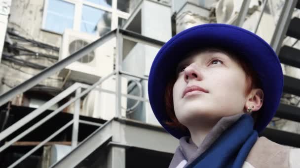 Arka plandaki endüstriyel merdivenlere bakan mavi şapkalı kadın portresi. — Stok video