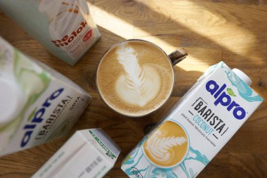 Ahşap bir masada bir fincan kapuçino ve alternatif süt türleri.