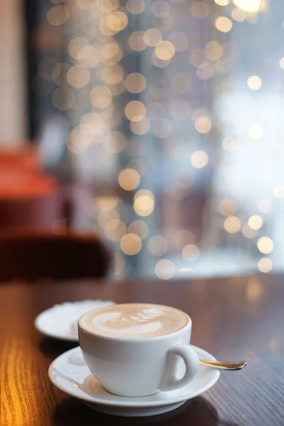 Una taza de café en una mesa en un café en el fondo de guirnaldas — Foto de Stock