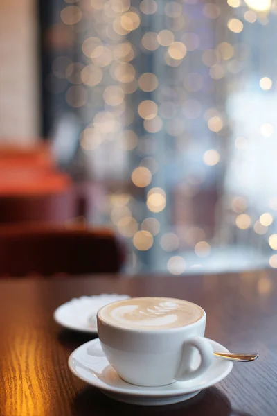 Een kopje koffie op een tafel in een café op de achtergrond van slingers — Stockfoto