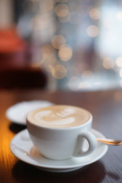 Una taza de café en una mesa en un café en el fondo de guirnaldas — Foto de Stock