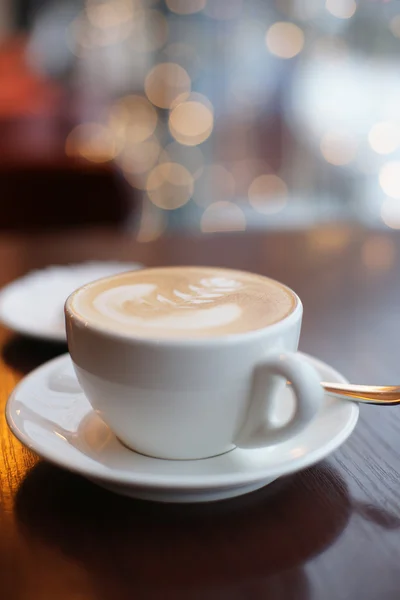 Una taza de café en una mesa en un café en el fondo de guirnaldas — Foto de Stock