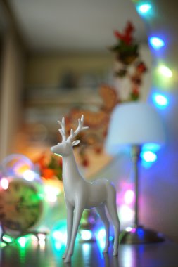 Beyaz Şifonyerin üstünde çelenk arka plan üzerinde bir geyik figürü