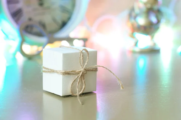 Small white box on the dresser on the background of garlands — Stock Photo, Image