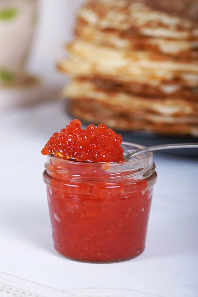 La banque de caviar rouge sur un fond de grande pile de crêpes sur la table — Photo