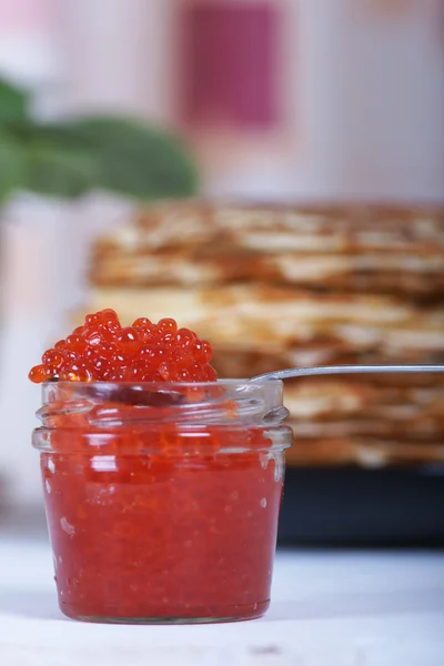 La banque de caviar rouge sur un fond de grande pile de crêpes sur la table — Photo