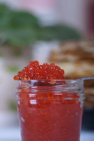 El banco de caviar rojo sobre un fondo de una gran pila de panqueques sobre la mesa —  Fotos de Stock