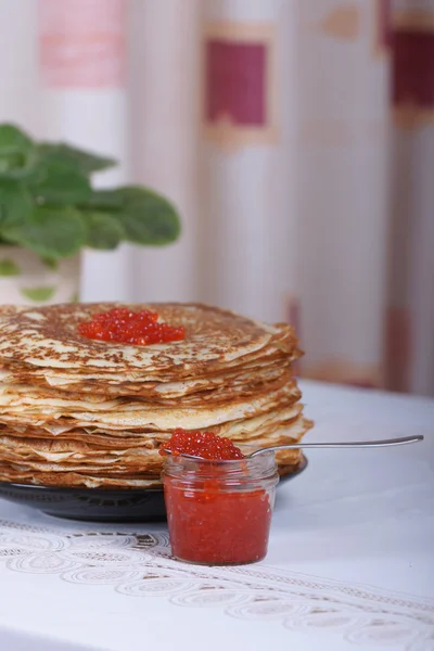 La banque de caviar rouge sur un fond de grande pile de crêpes sur la table — Photo