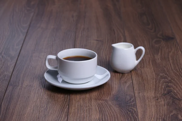 Κούπα με μαύρο καφέ και γάλα κανάτα στο ξύλινο φόντο — Φωτογραφία Αρχείου