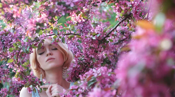 Jovem mulher em flores rosa — Fotografia de Stock