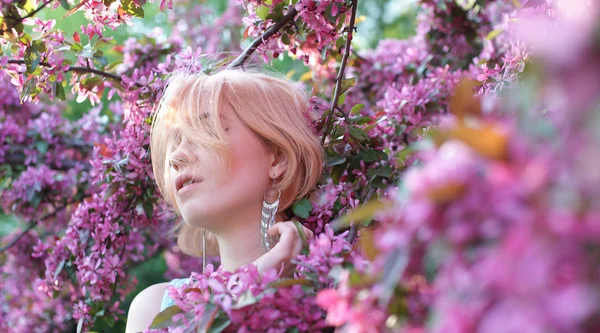 Jovem mulher em flores rosa — Fotografia de Stock