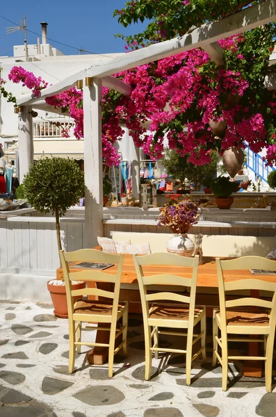 Restaurante bajo los árboles con flores en la calle de Chora Mykonos —  Fotos de Stock