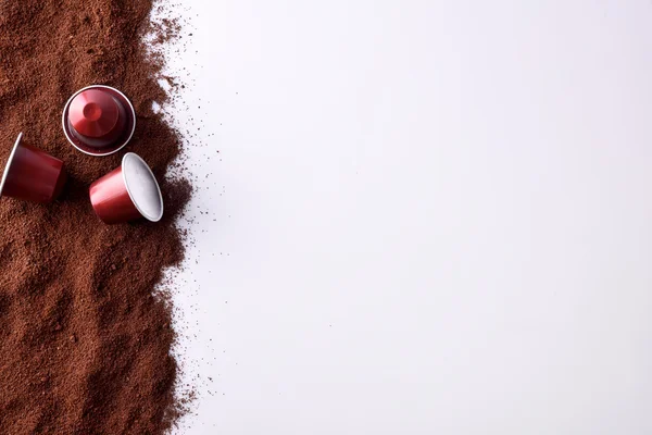 Drie capsules van espresso op gemalen koffie top uitzicht — Stockfoto