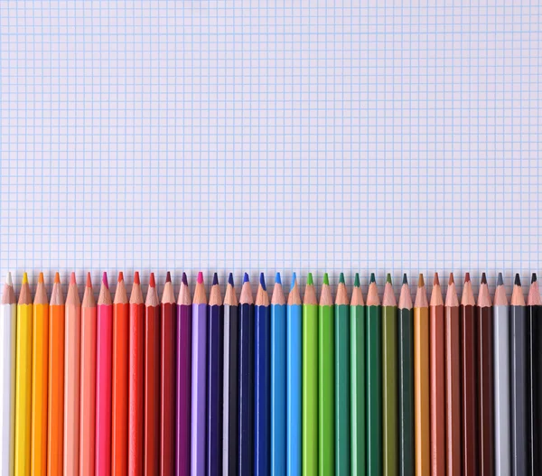 Colored pencils lined up palette on checkered white sheet