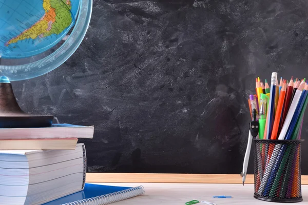 Skrivbord med skolan verktyg och blackboard — Stockfoto