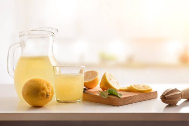 Taze sıkılmış limon suyuyla dolu sürahi ve bardak mutfak tezgahında kesilmiş meyve. Ön manzara. Yatay bileşim.