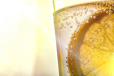 Soda katılmış limon dilimleri kristal bir bardakta güneş ışığı görüşlü.